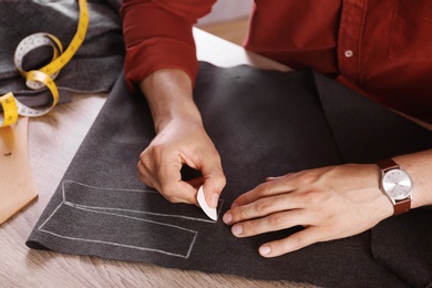 Tailor working with cloth at table in atelier