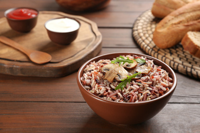 Photo of Delicious brown rice in bowl on wooden table