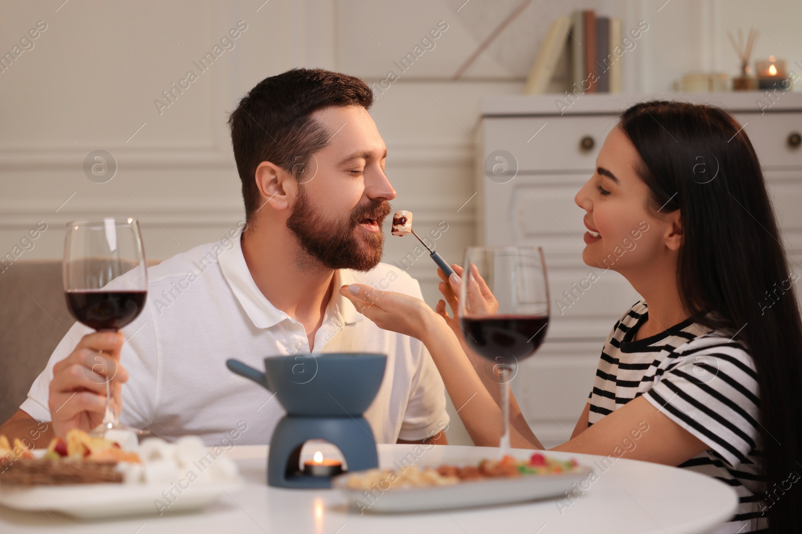 Photo of Affectionate couple enjoying chocolate fondue during romantic date at home