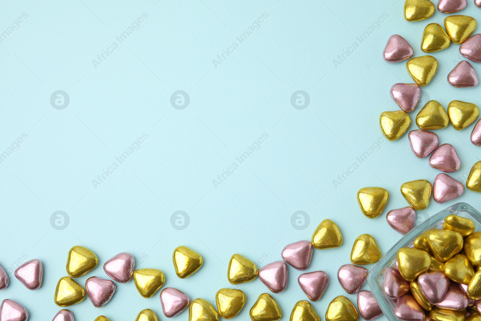 Photo of Many delicious heart shaped candies on light blue background, flat lay. Space for text