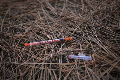 Photo of Disposable syringe with needle on heap of dry branches