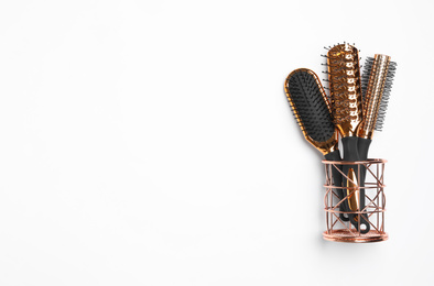 Modern hair brushes in holder on white background, top view