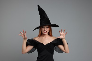 Photo of Young woman in scary witch costume on light grey background. Halloween celebration