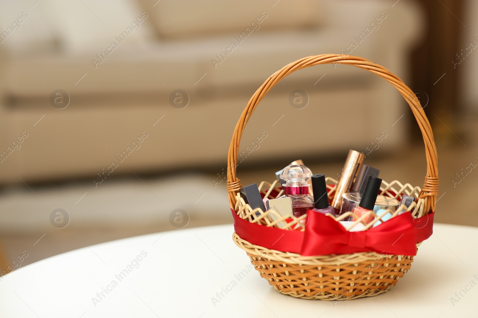 Photo of Wicker basket full of gifts on white table in living room. Space for text