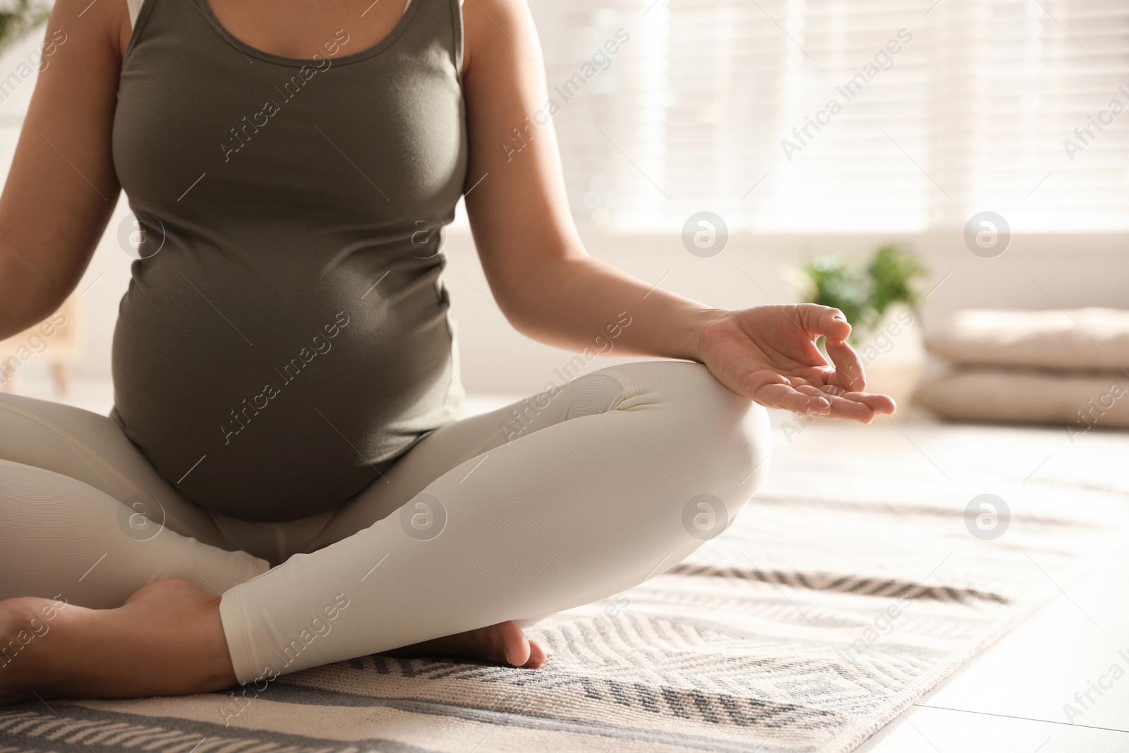 Photo of Young pregnant woman practicing yoga at home, closeup