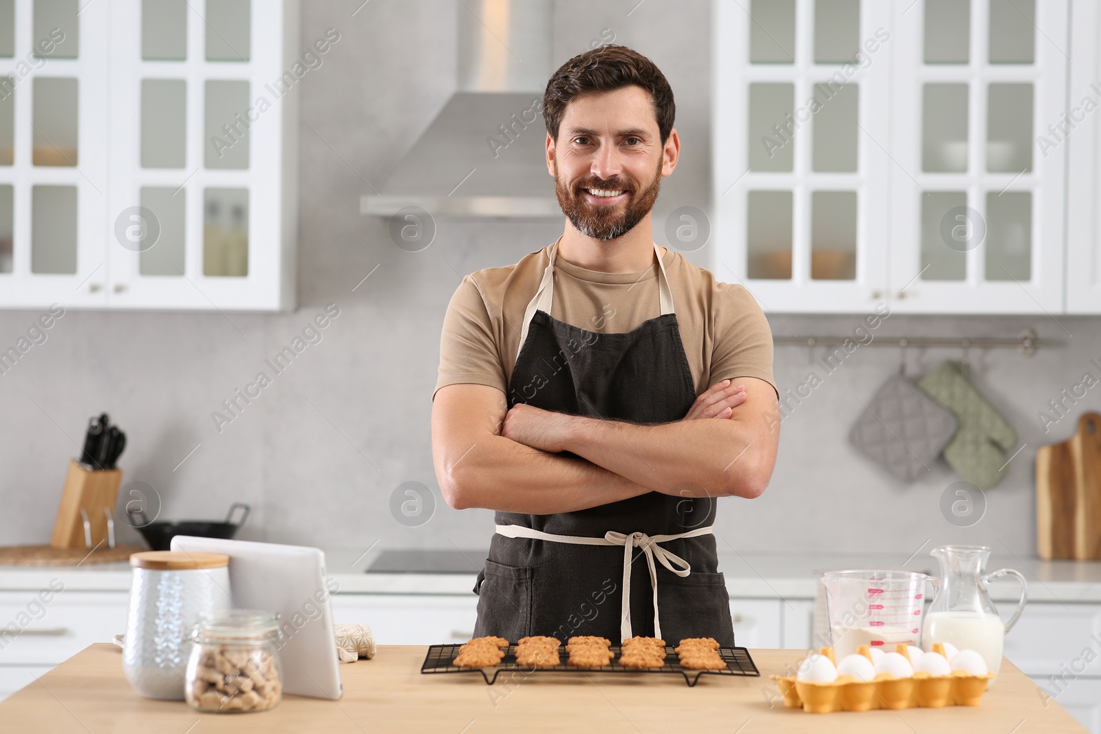 Photo of Man with freshly baked cookies at table in kitchen. Online cooking course