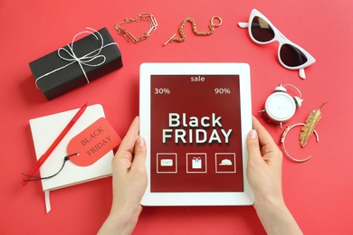 Photo of Woman with tablet surrounded by stylish accessories on red background, top view. Black Friday sale