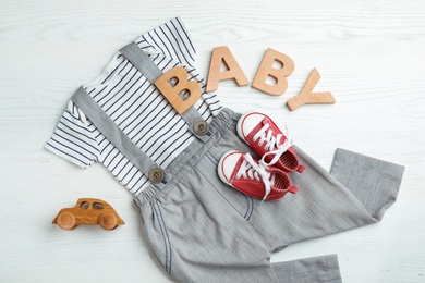 Photo of Flat lay composition with cute clothes on white wooden background. Baby accessories