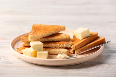 Photo of Tasty toasts with butter served on white wooden table, closeup