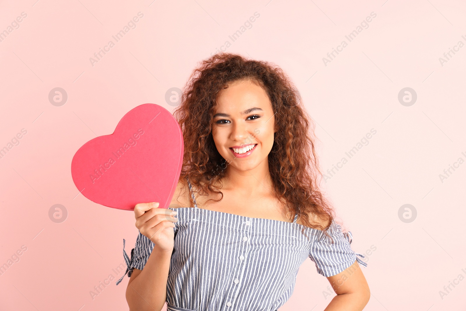 Photo of African-American woman with heart shaped box on color background