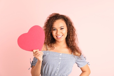 African-American woman with heart shaped box on color background