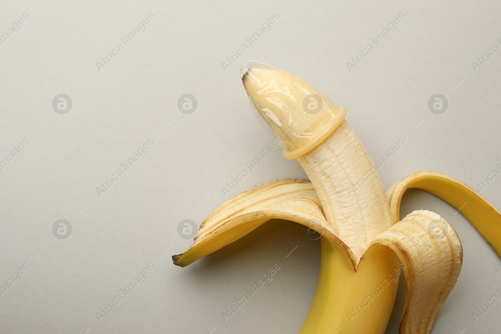 Photo of Banana with condom on light grey background, top view and space for text. Safe sex