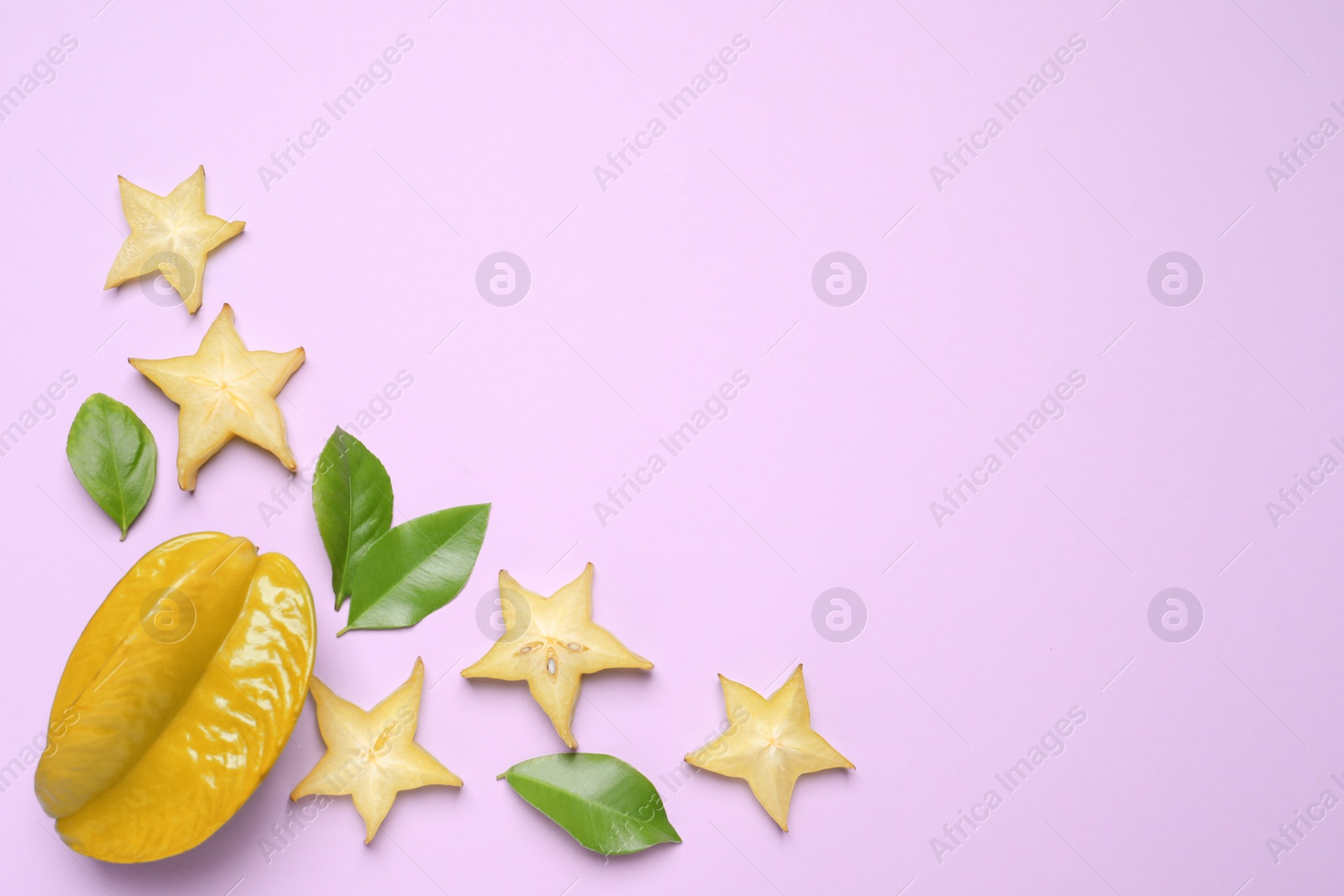 Photo of Delicious carambola fruits on violet background, flat lay. Space for text