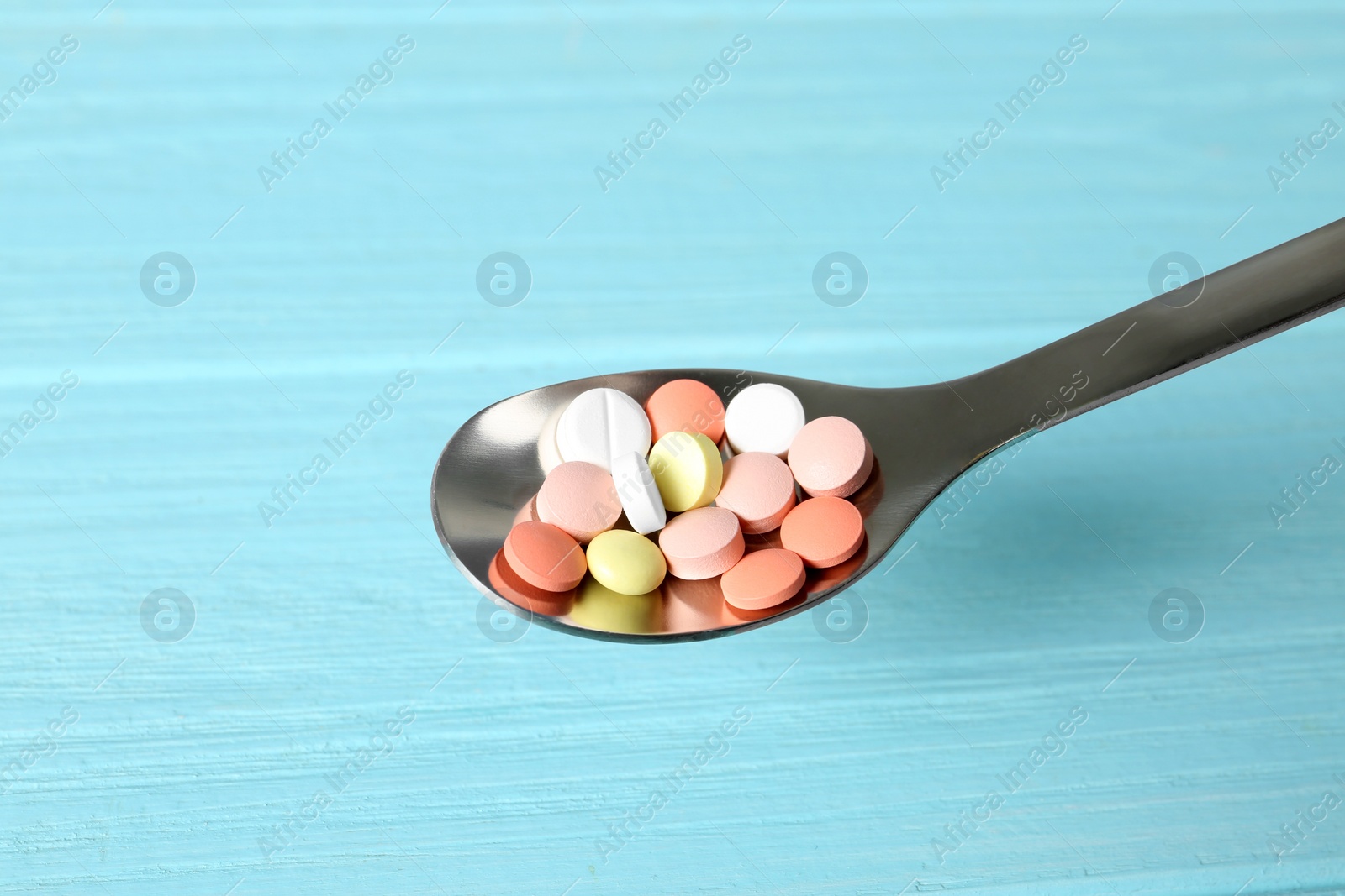 Photo of Spoon with weight loss pills on color background