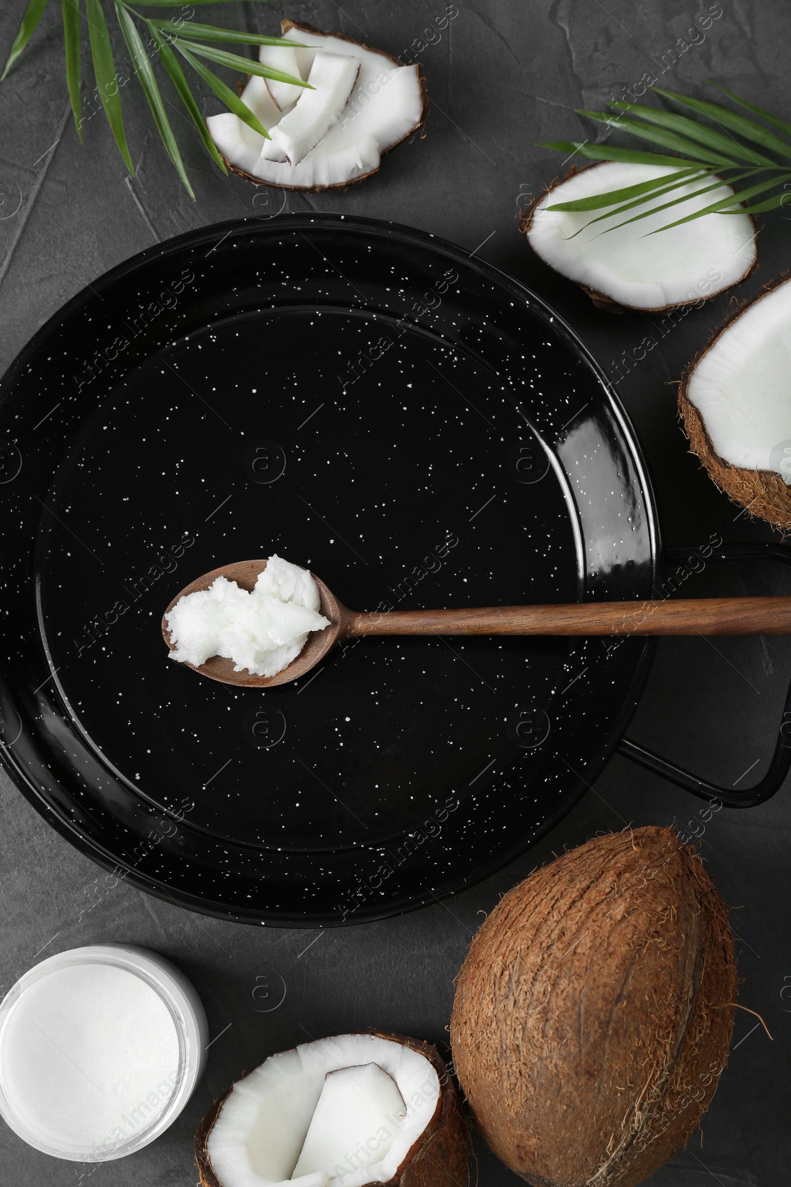 Photo of Flat lay composition with frying pan and organic coconut cooking oil on grey table