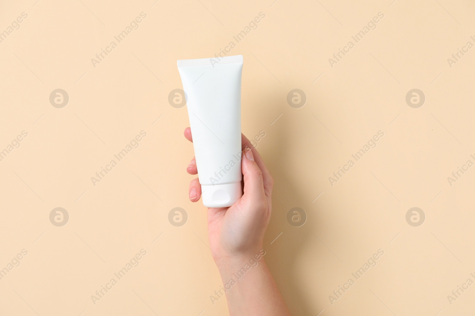 Photo of Woman with tube of hand cream on beige background, top view