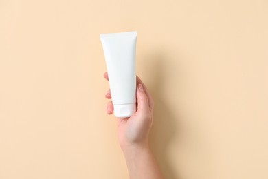 Photo of Woman with tube of hand cream on beige background, top view