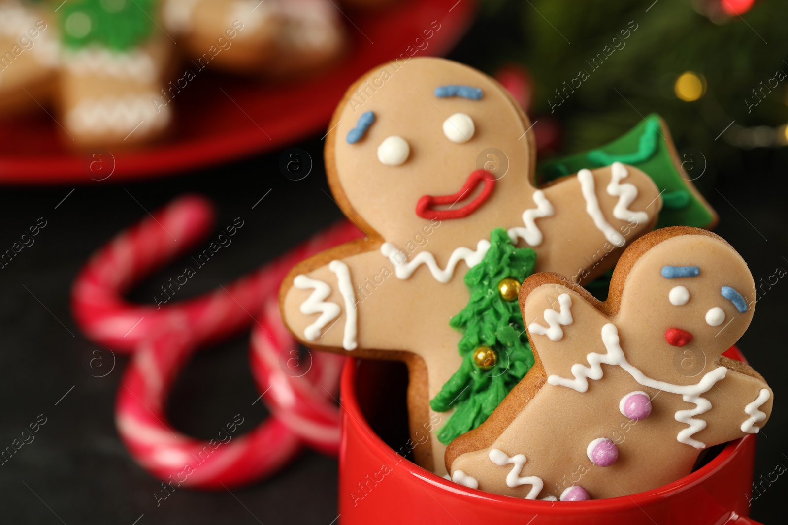 Photo of Delicious homemade Christmas cookies in cup against blurred festive lights, closeup