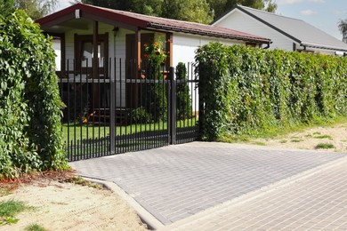 Photo of Closed metal gates near houses and green hedge