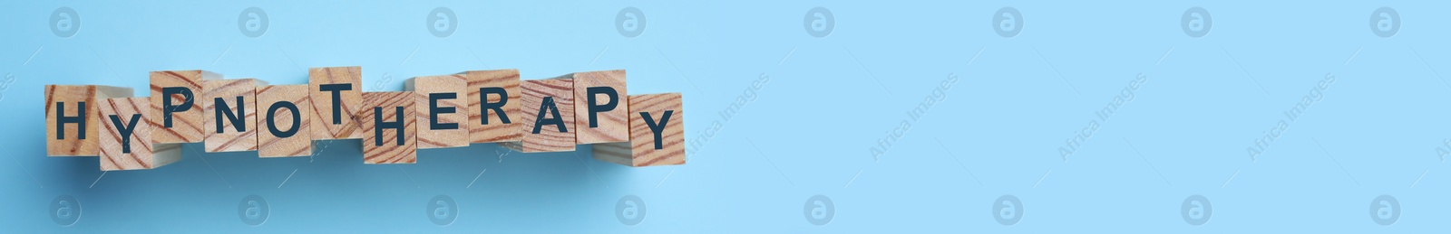 Photo of Wooden blocks with word HYPNOTHERAPY on light blue background, flat lay