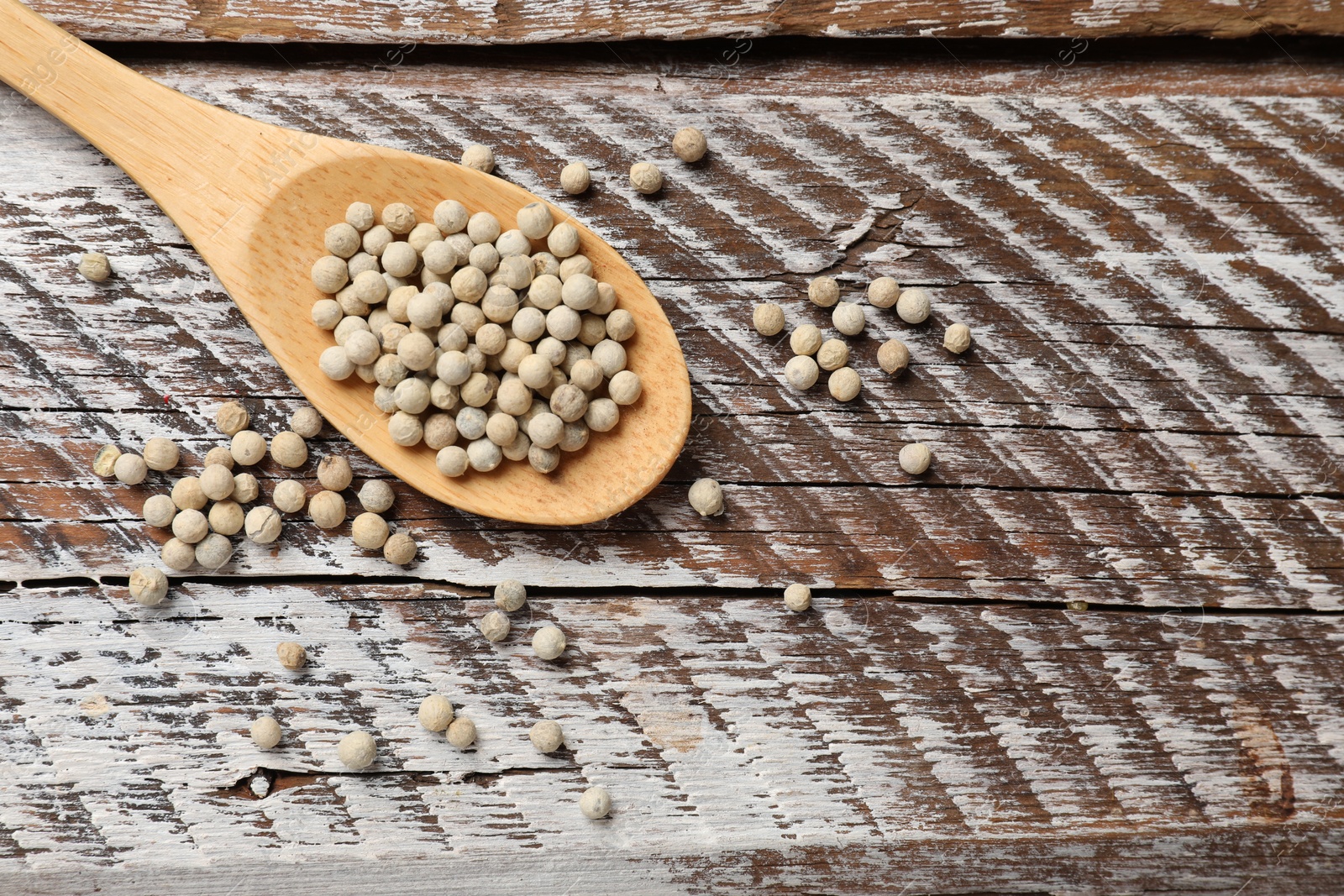 Photo of Aromatic spice. White pepper in spoon on wooden table, top view. Space for text