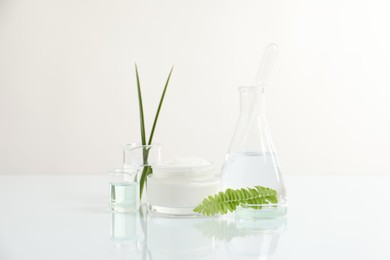 Photo of Organic cosmetic product, natural ingredients and laboratory glassware on white table