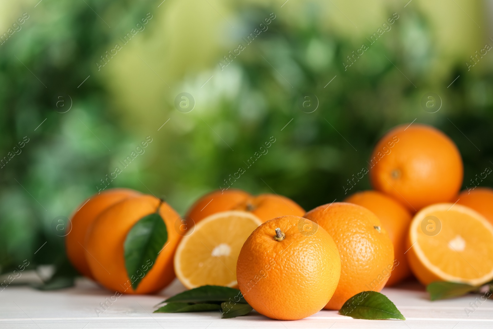 Photo of Fresh ripe oranges on white table against blurred background. Space for text