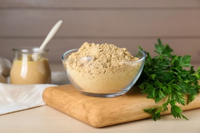 Photo of Bowl of aromatic mustard powder and parsley on wooden table