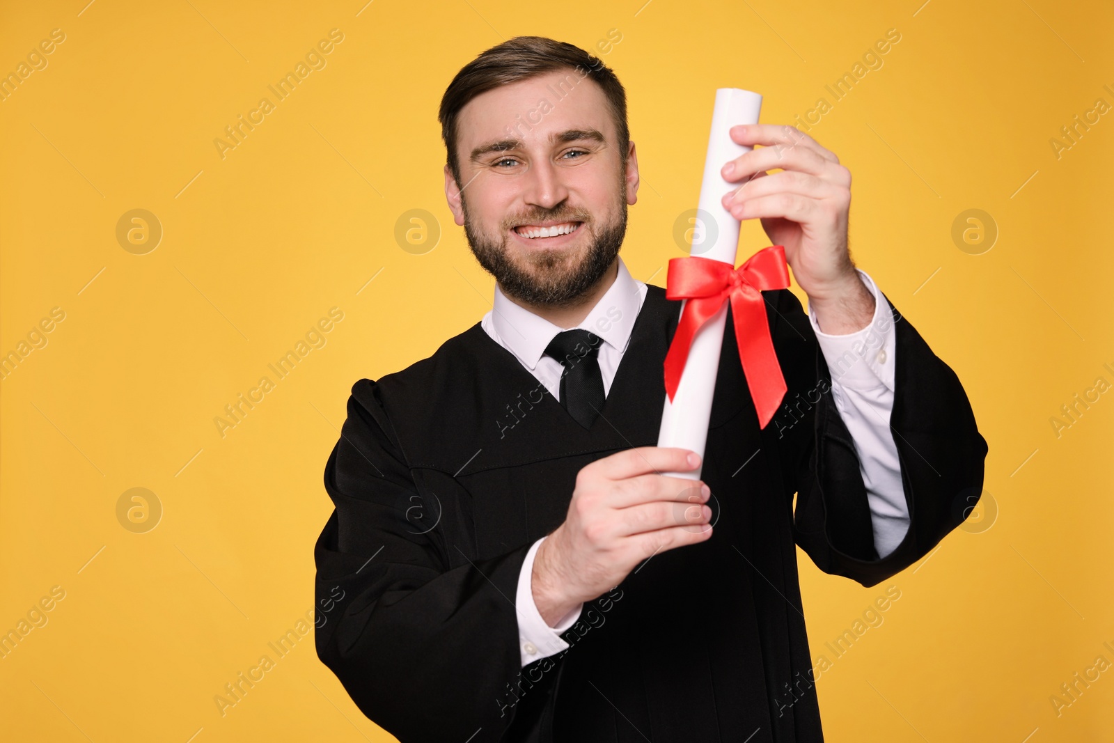 Photo of Happy student with diploma on yellow background