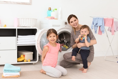 Photo of Housewife with little children doing laundry at home