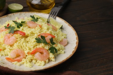 Photo of Delicious risotto with shrimps, parsley and lime on wooden table, closeup