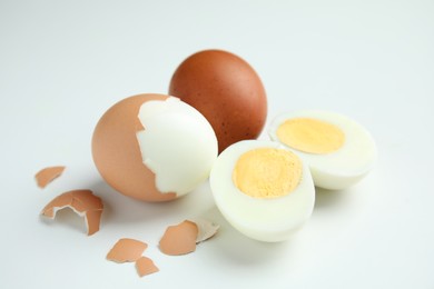 Photo of Hard boiled eggs and pieces of shell on white background