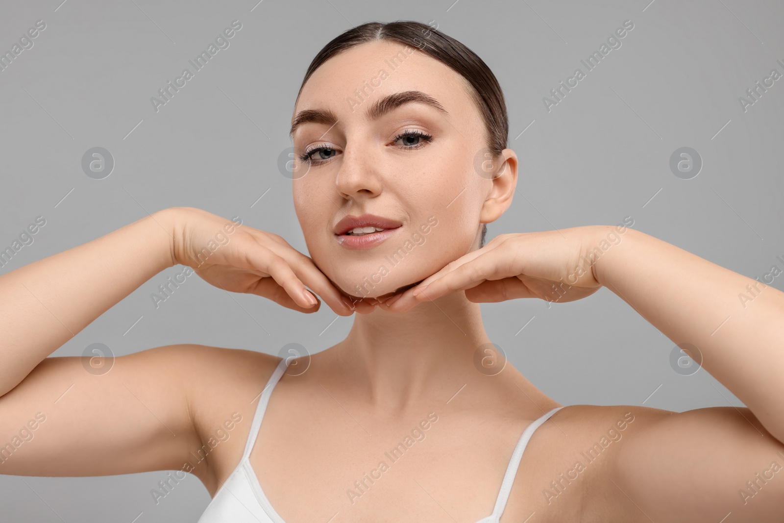 Photo of Beautiful woman touching her chin on grey background