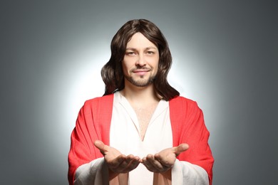 Photo of Jesus Christ reaching out his hands on grey background