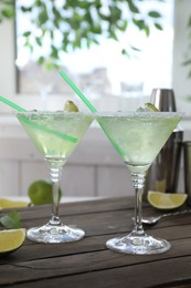 Delicious Margarita cocktail in glasses and lime on wooden table