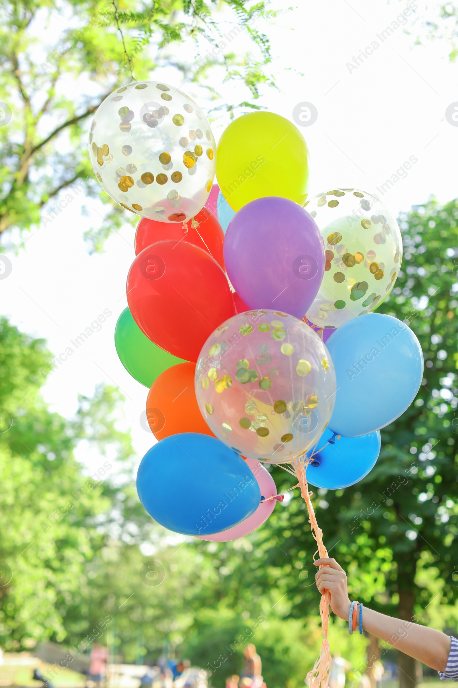 Photo of Young woman with colorful balloons outdoors on sunny day