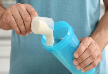 Man preparing protein shake in kitchen, closeup