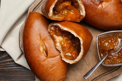 Photo of Delicious baked patties with jam on wooden table, flat lay