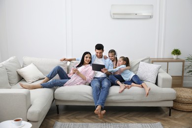 Image of Happy family resting under air conditioner on white wall at home