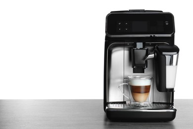 Photo of Modern coffee machine with glass cup of latte on wooden table against white background. Space for text