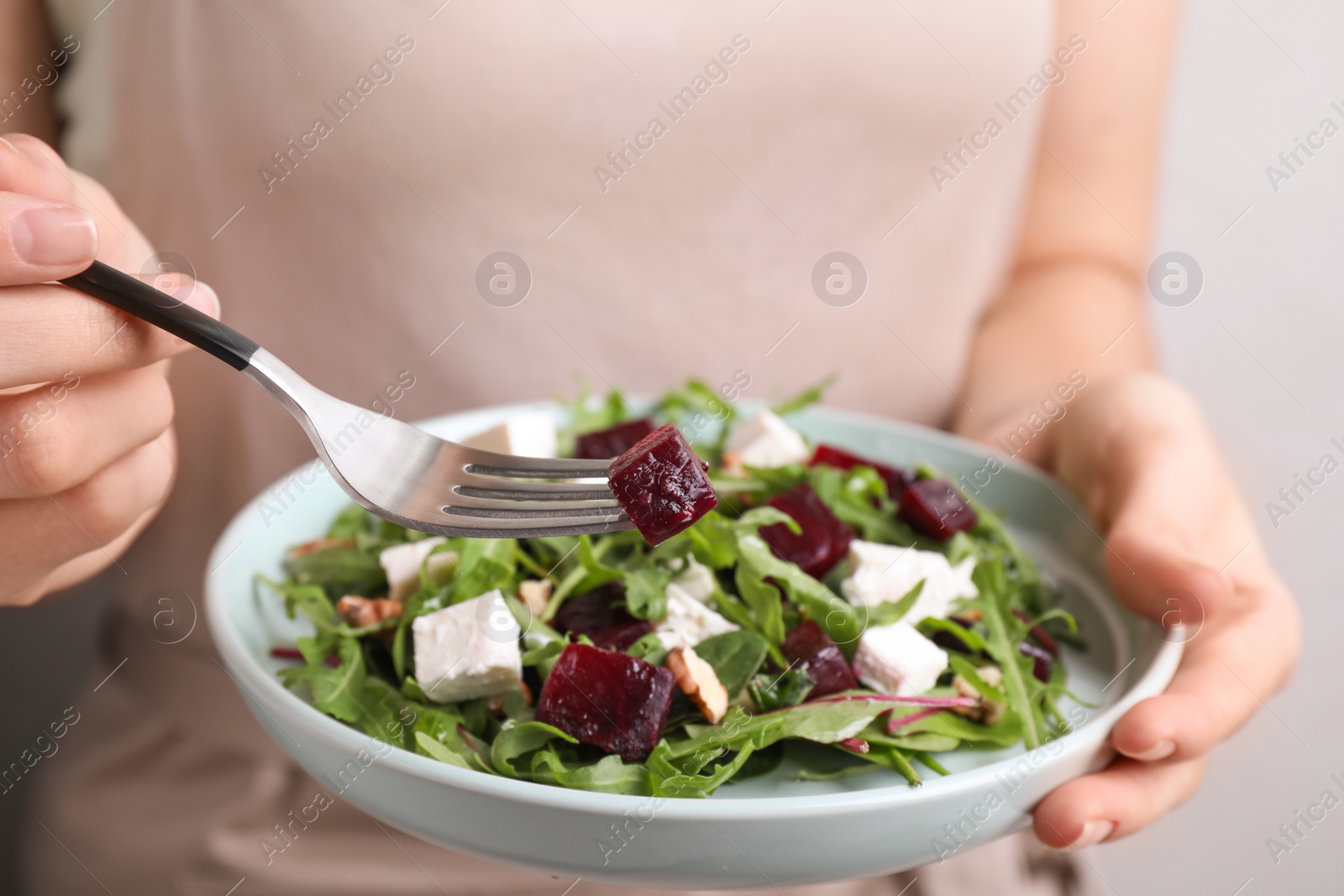 Photo of Woman with fresh delicious beet salad on light background, closeup