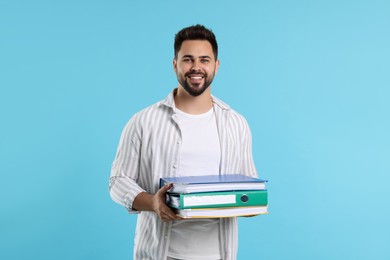Photo of Happy man with folders on light blue background