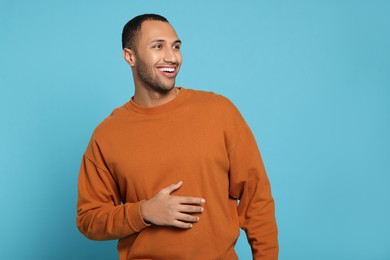 Portrait of happy African American man on light blue background. Space for text