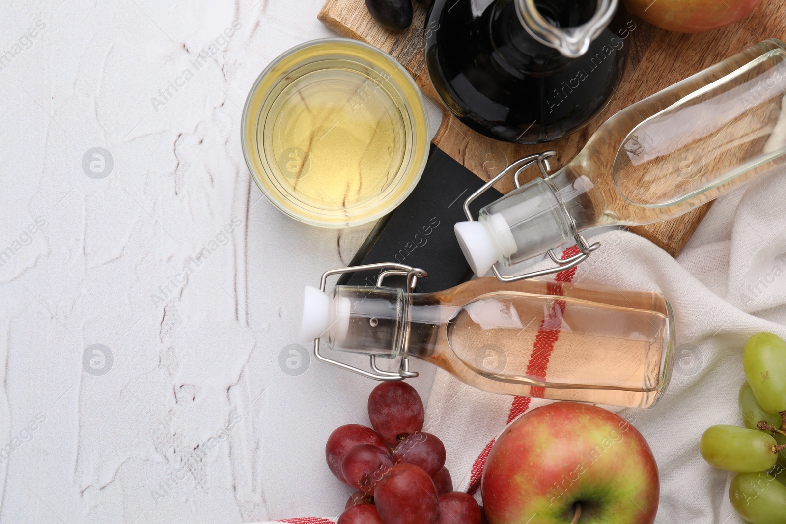 Photo of Different types of vinegar and fresh fruits on white table, top view. Space for text