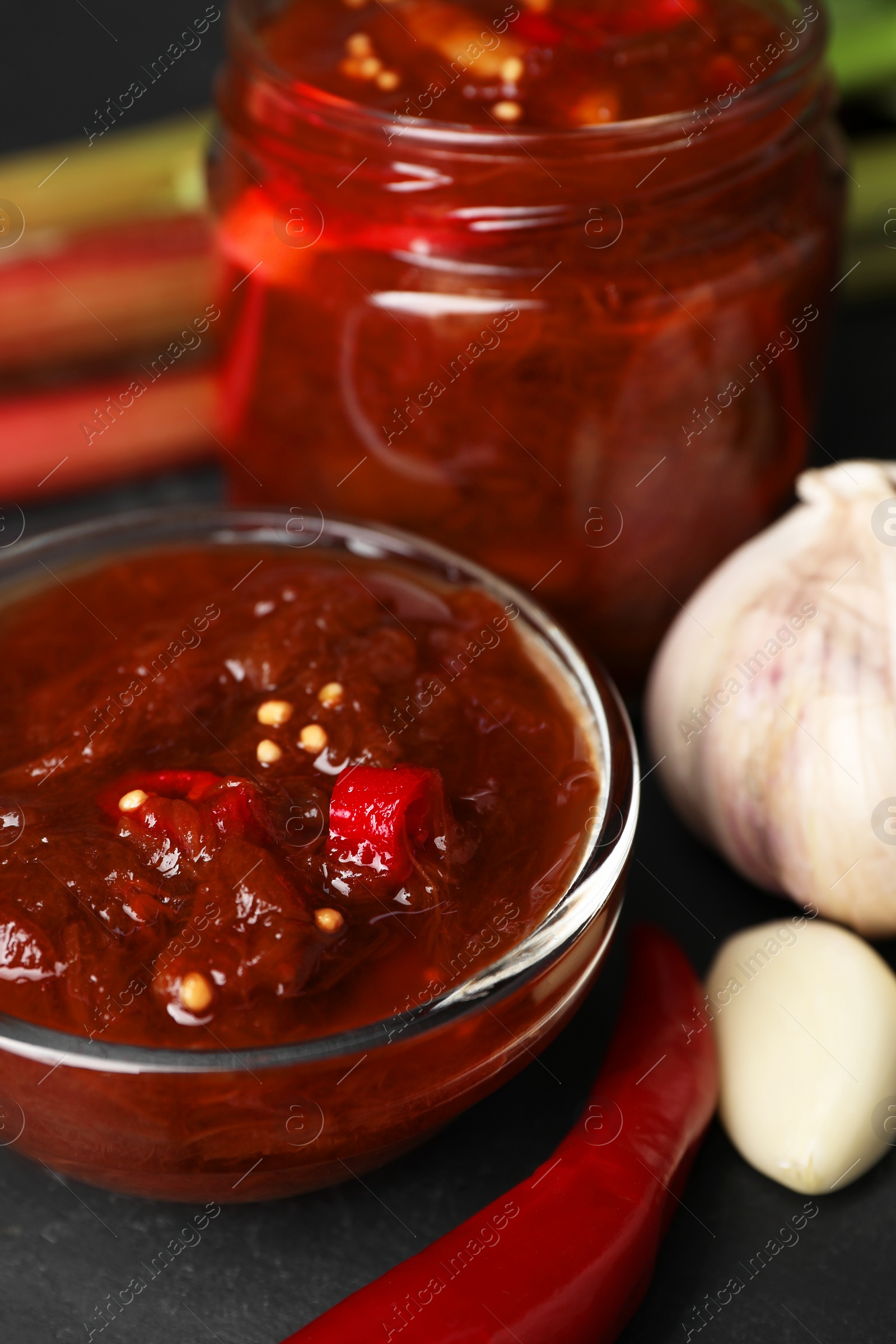 Photo of Tasty rhubarb sauce and ingredients on black table, closeup