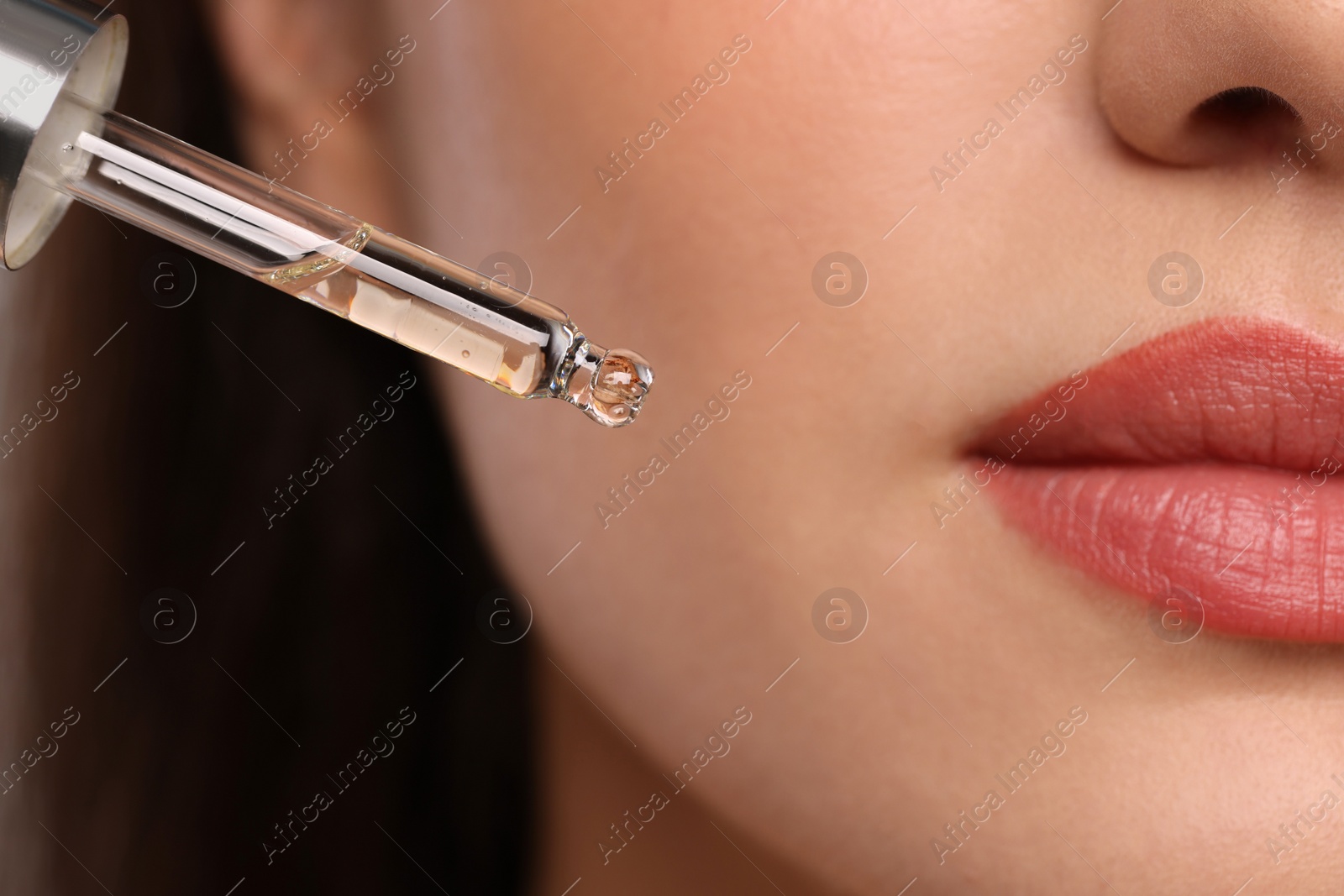 Photo of Young woman applying essential oil onto face, closeup