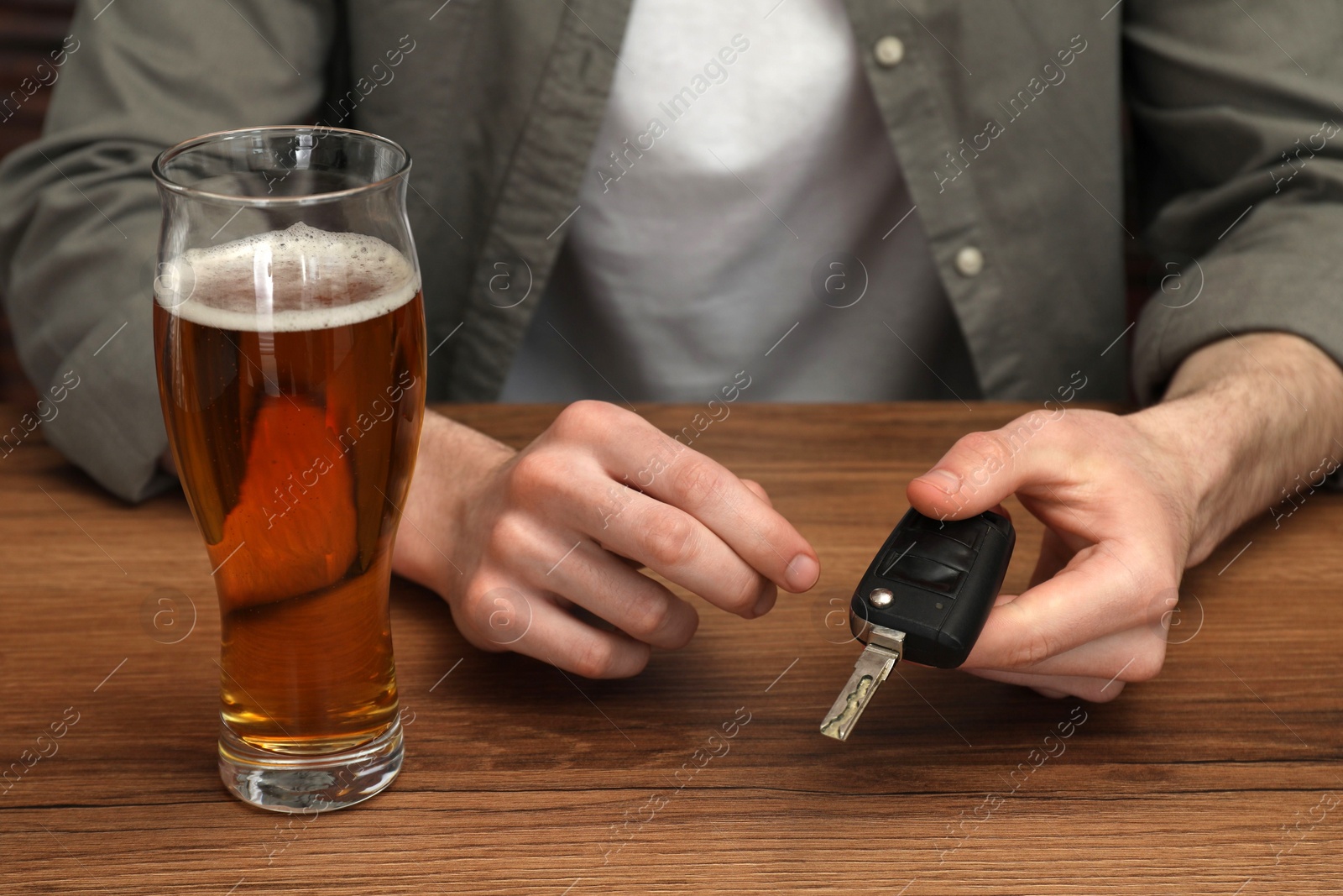 Photo of Man holding car key at table with glass of alcoholic drink, closeup. Don't drink and drive concept