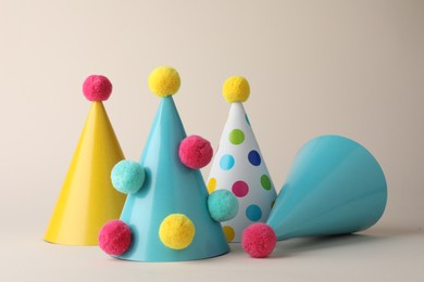 Photo of Colorful party hats with pompoms on beige background