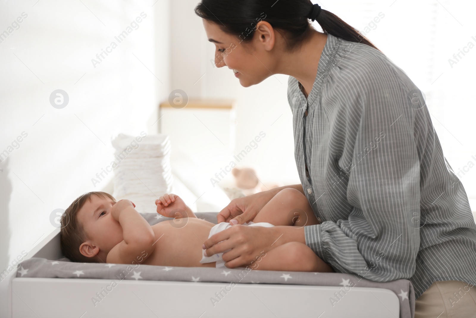 Photo of Mother changing baby's diaper on table at home