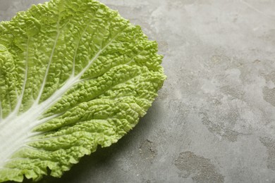 Photo of Fresh Chinese cabbage leaf on gray textured table, top view. Space for text